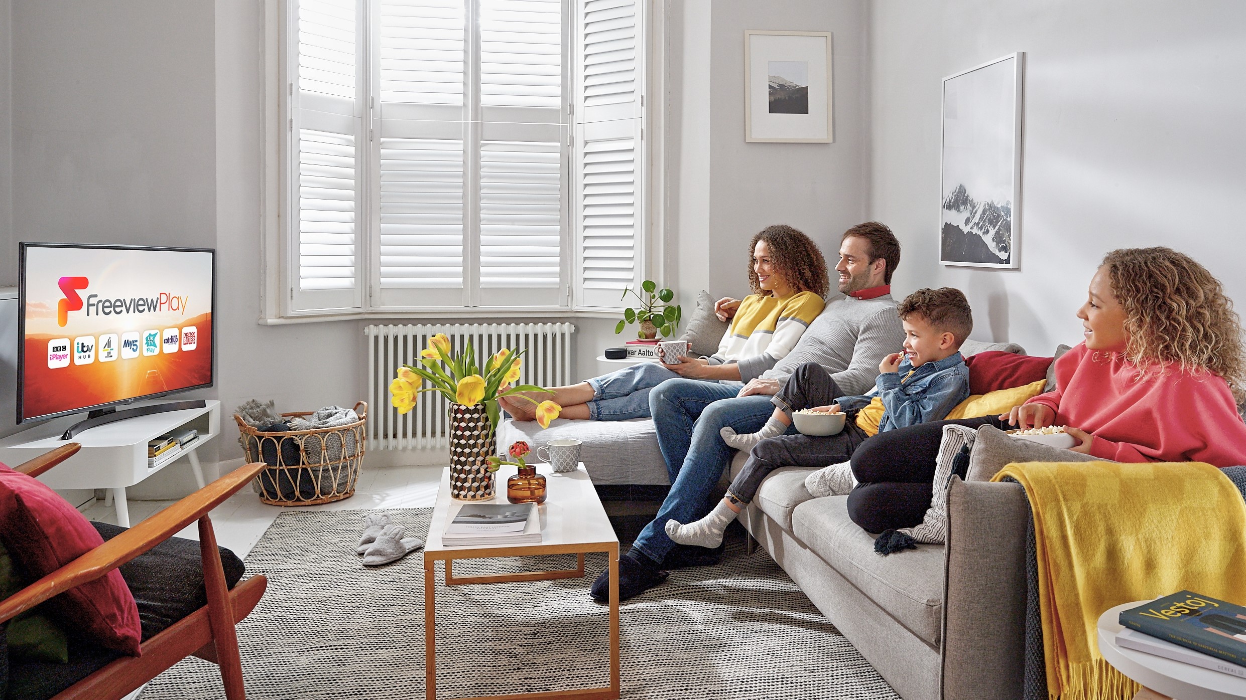 Family seated on a sofa watching Freeview Play