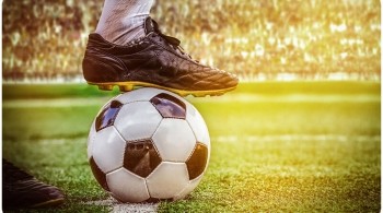 Close up of a football player with foot placed on top of a football