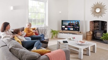 Three people seated on a sofa, watching TV